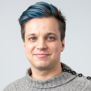 A person with blue and black hair wearing a grey sweater