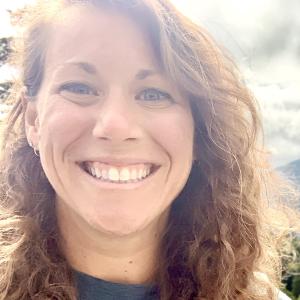 Person with copper curly hair smiling at the camera