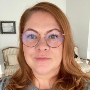 Woman with shoulder-length reddish hair and glasses