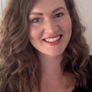 Person with brown curly long hair smiling
