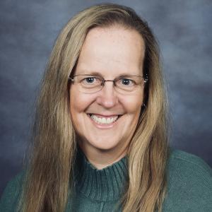 A person wearing glasses and a green sweater