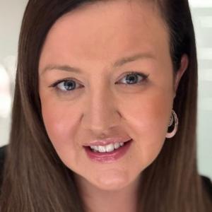 A person with long brown hair smiling