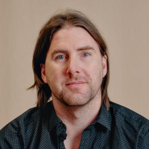 Photo of man with shoulder-length hair and black shirt