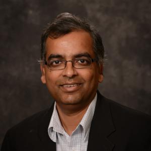 Person in front of a grey background wearing a black jacket