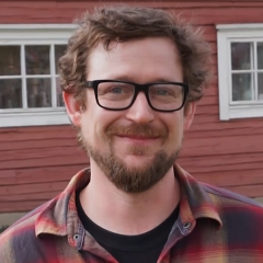 2018-2019 U.S. Fulbright Fellow Jonathan Capps smiling in front of a red wooden house