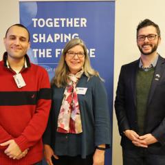 Group photo of Isaac Farhadian, Anne Boyette and Ryan Lewis in front of the Fulbright Finland Foundation's roll-unp with words Together Shaping the Future on a blue background.