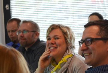 Three men and one woman looking at something during orientation and laughing.