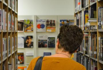 A short-haired girl between to shelves full of books in a library