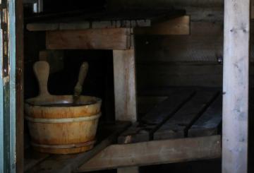 Open door to a sauna, showing a wooden water bucket